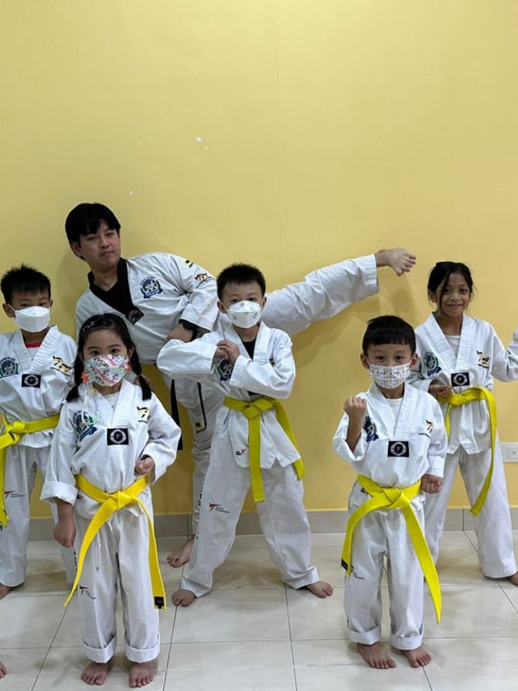 Children in taekwondo uniforms with their coach